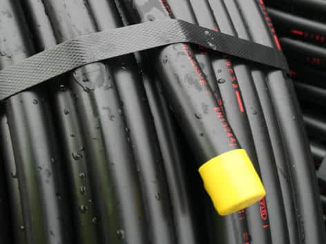 Close-up of coiled black cables bound with a strap; one cable has a yellow protective end cap.