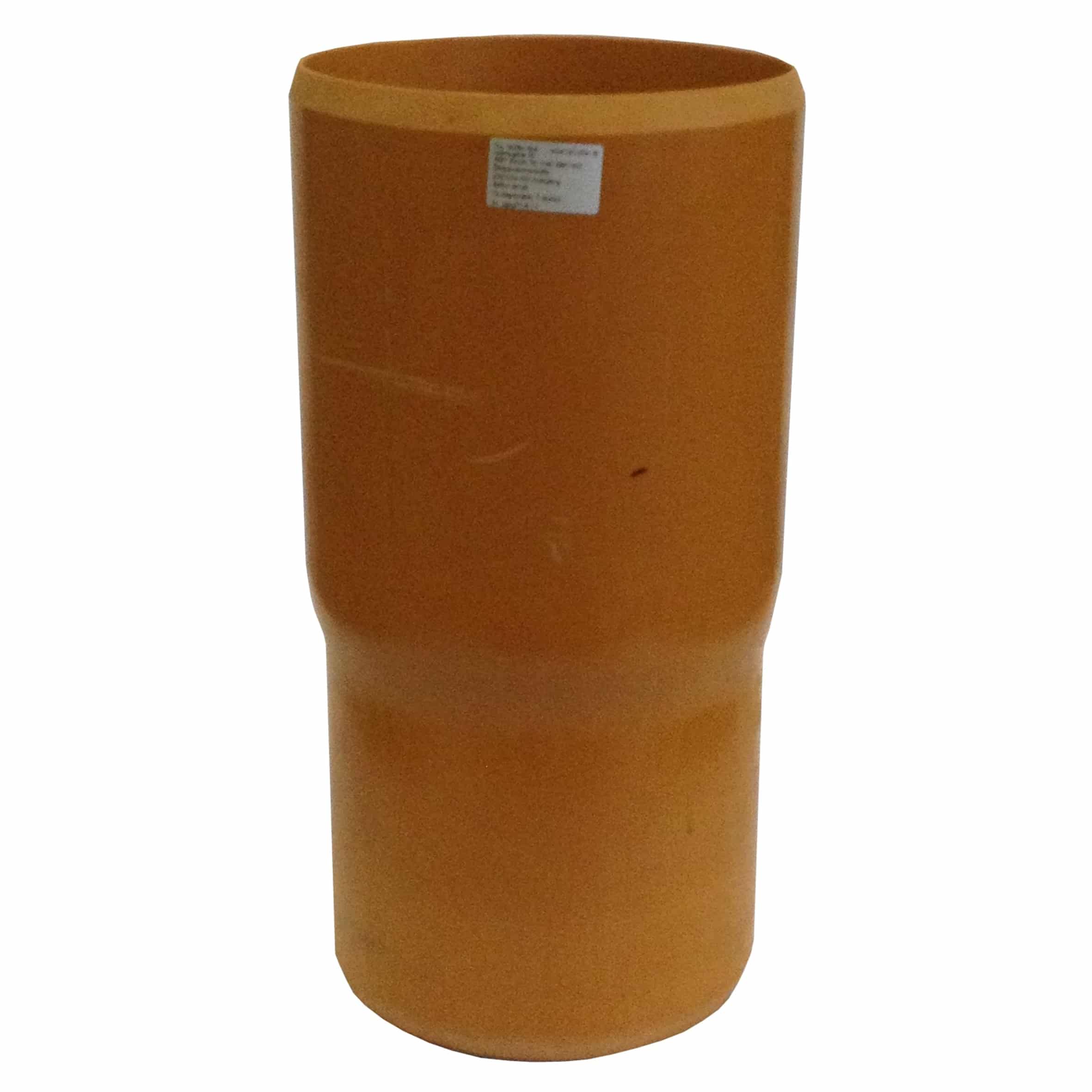 Orange cylindrical planter with a small silver label on its side in the foreground from a front-facing angle?