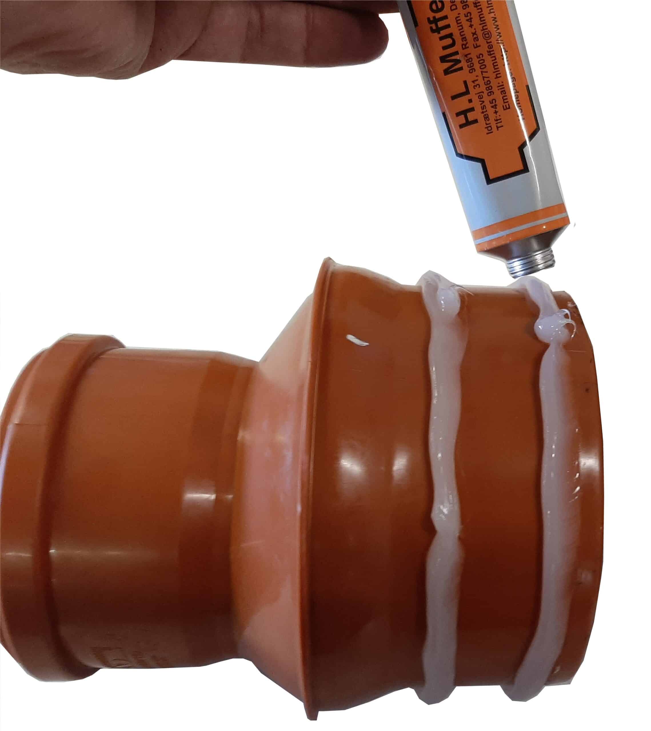 Close-up of a hand squeezing an orange tube to apply white sealant onto an orange plastic part.