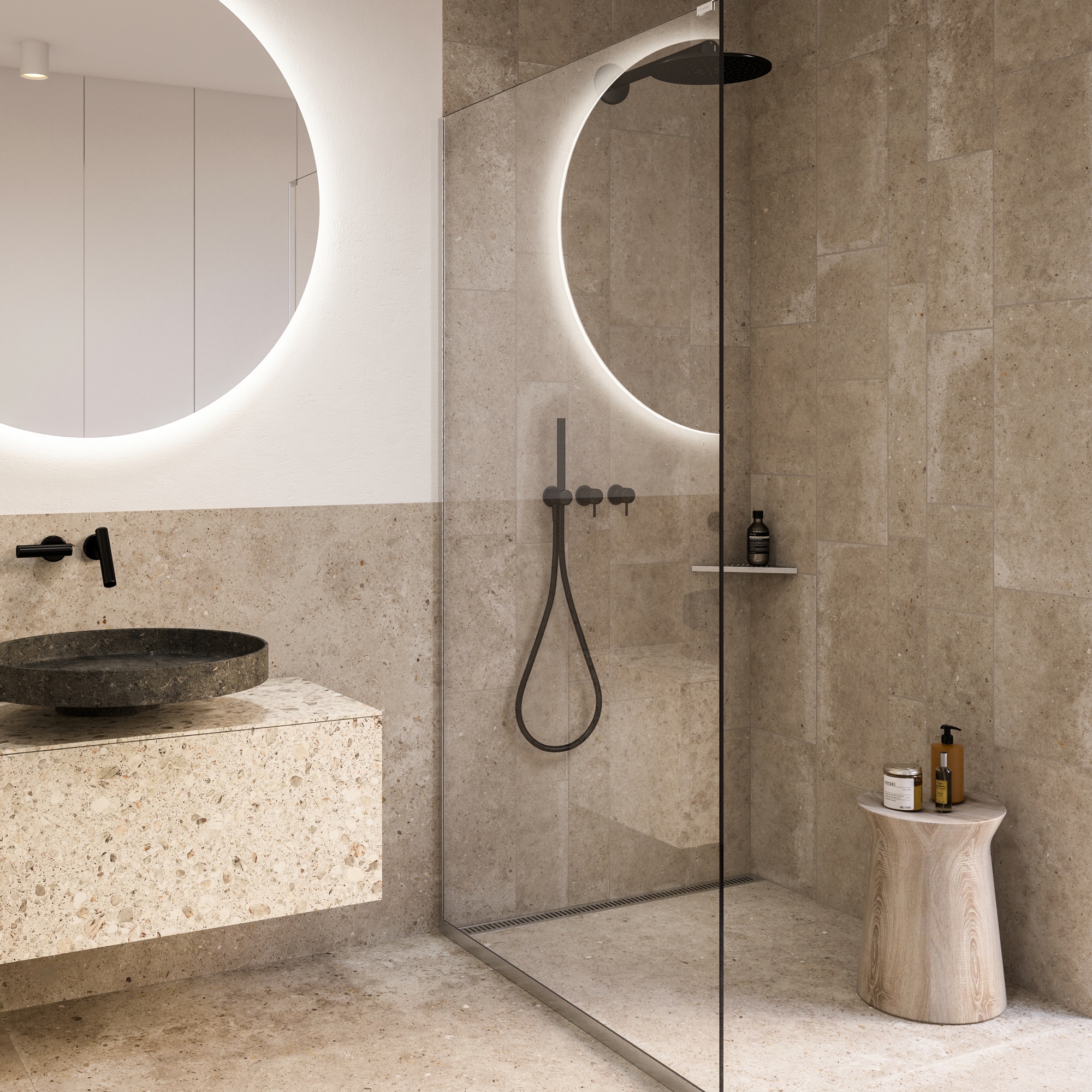 Minimalist bathroom with a backlit circular mirror, terrazzo counter, round stone sink, and glass‑walled shower.