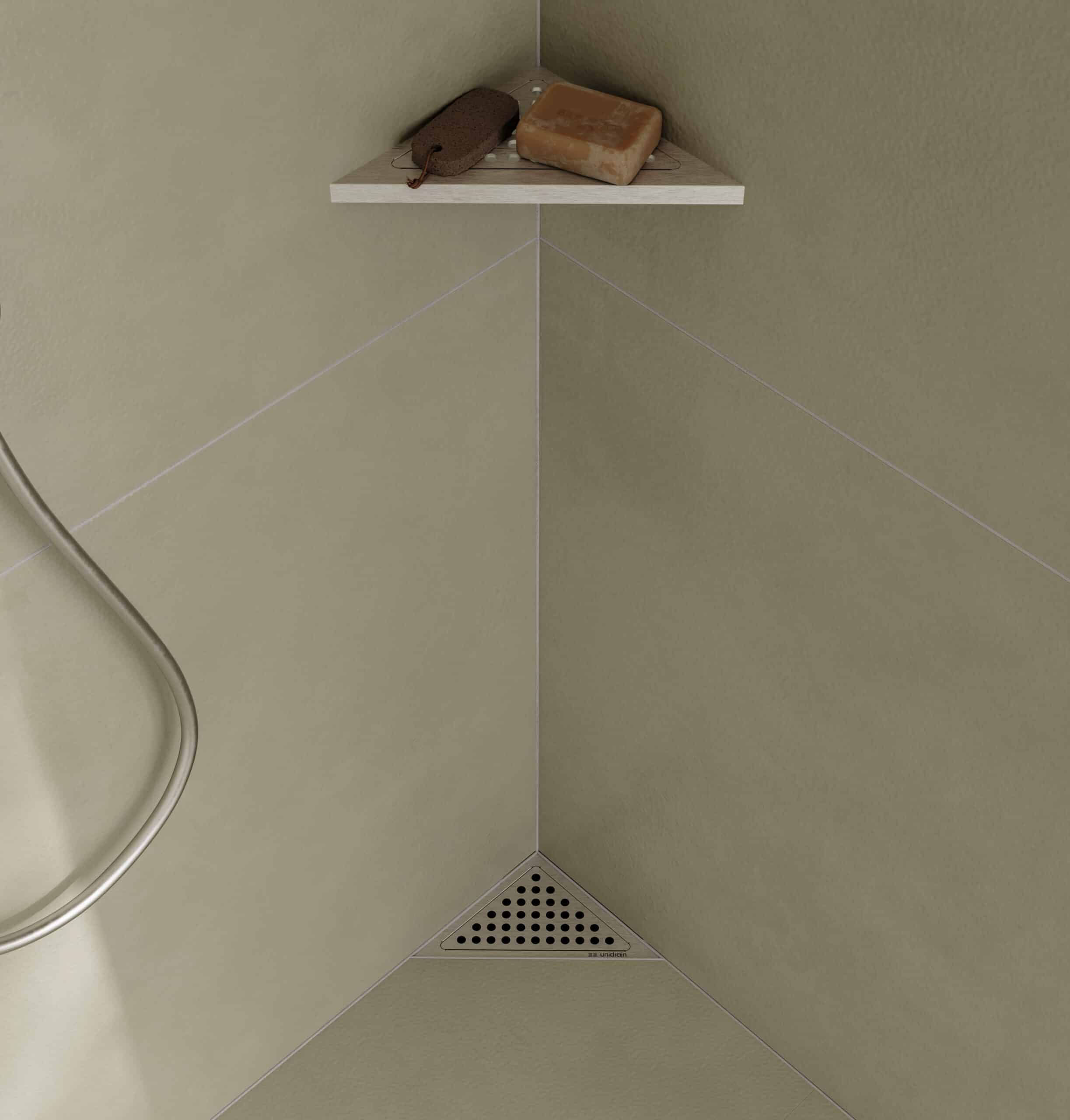 Soap bars resting on a small wooden shelf in the corner of a tiled shower stall, beige walls and a triangular metal drain visible below.