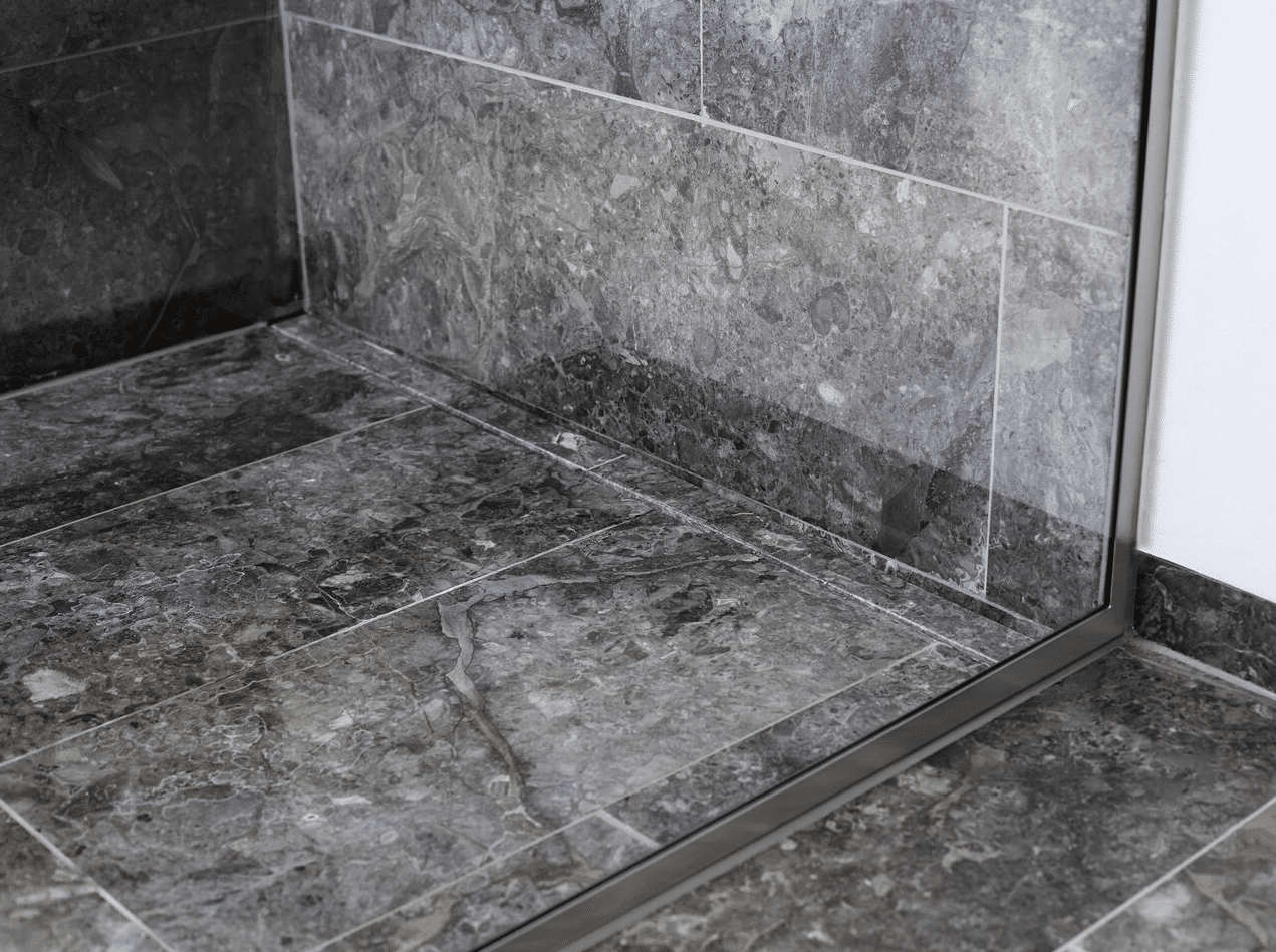 Gray marble tiled shower corner with a glass door and metal frame mentioned in a bathroom context.