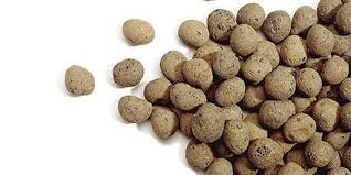 Pile of small round brown dry pet food kibble spilled on a white background.