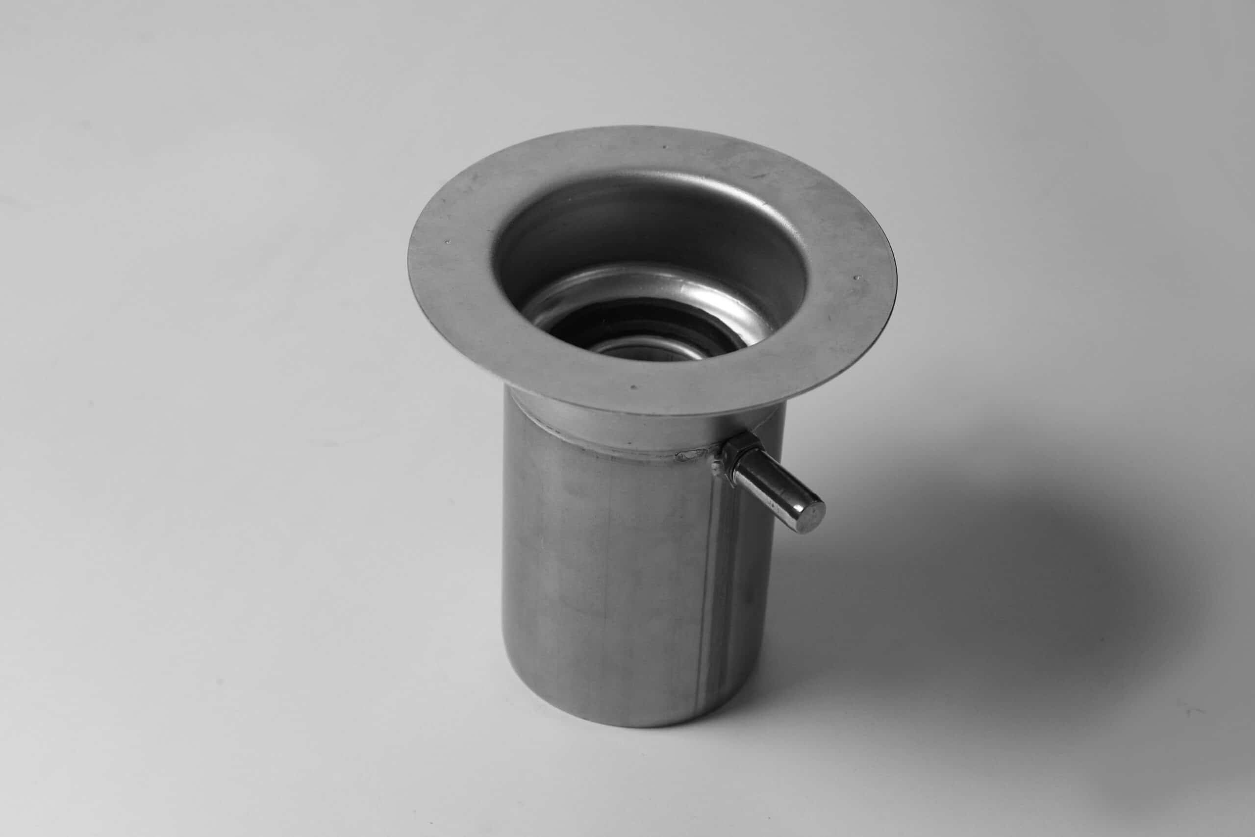 Close-up of a metal plumbing pipe with a wide circular top flange and side control lever, viewed from above