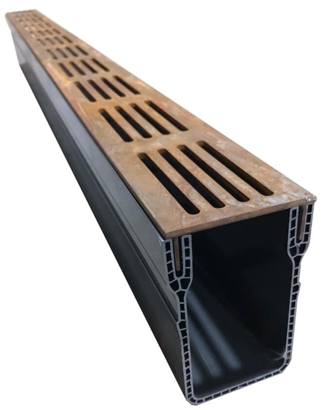 Long rectangular trench drain with a rusted slotted metal grate on top and a black plastic trough beneath.